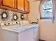 Bright laundry room with window, white washer and dryer, and overhead storage at 3664 Se 45Th Pl, Ocala, FL 34480