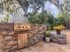 Outdoor kitchen with stainless steel grill, stone veneer, and lush landscaping at 3664 Se 45Th Pl, Ocala, FL 34480