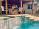 Inviting pool with waterfall feature, stone surround, and cozy seating area and outdoor kitchen at 3664 Se 45Th Pl, Ocala, FL 34480