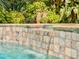 Inviting pool with tiled waterfall feature, stone surround, and lush tropical vegetation at 3664 Se 45Th Pl, Ocala, FL 34480