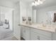 Bright bathroom features double sinks, quartz countertop, and a view into an adjacent carpeted room at 391 Cheeota Ct, Minneola, FL 34715