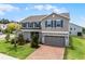 Two-story home with a brick driveway, lush green grass, and a neutral colored exterior at 391 Cheeota Ct, Minneola, FL 34715