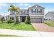 Two-story home showcasing beautiful landscaping, a brick driveway and neutral colored exterior at 391 Cheeota Ct, Minneola, FL 34715