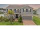 Charming two-story home with a brick driveway, blue shutters, and tropical landscaping at 391 Cheeota Ct, Minneola, FL 34715