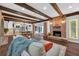 Inviting living room featuring exposed wood beams, brick fireplace, hardwood floors, and views of the kitchen at 4219 Magnolia Ave, Leesburg, FL 34748