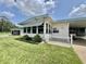 Welcoming single-story home featuring a well-manicured lawn, a picket fence, and covered carport at 424 Hawthorne Blvd, Leesburg, FL 34748