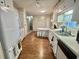 Well-lit kitchen featuring white cabinetry, a practical layout, and wood-look flooring at 424 Hawthorne Blvd, Leesburg, FL 34748