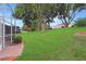 Serene backyard with lush green lawn and established trees, viewed from screened porch at 5008 Sawgrass Lake Cir, Leesburg, FL 34748