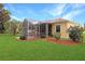 Expansive backyard featuring a screened lanai with brick flooring, lush lawn, and attractive landscaping at 5008 Sawgrass Lake Cir, Leesburg, FL 34748