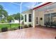 The screened lanai with brick flooring overlooks the yard with tropical plants and a serene outdoor view at 5008 Sawgrass Lake Cir, Leesburg, FL 34748