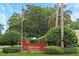 Community sign at Sawgrass Village surrounded by manicured landscaping and mature trees at 5008 Sawgrass Lake Cir, Leesburg, FL 34748
