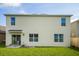 Back exterior view features a sliding glass door and simple patio in a lawn at 5386 Pine Lilly Dr, St Cloud, FL 34771