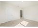 Clean, carpeted bedroom with white walls, featuring a closed door and an open doorway to another room at 5386 Pine Lilly Dr, St Cloud, FL 34771