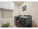 A laundry room with sleek, dark-colored washer and dryer units and overhead cabinets for storage at 5386 Pine Lilly Dr, St Cloud, FL 34771