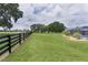 Sprawling backyard featuring lush green grass, black fencing, mature trees and a screened-in pool at 5429 County Road 125, Wildwood, FL 34785