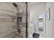 Modern tiled shower with a rainfall showerhead and seamless glass door, leading to a bright outdoor view at 5429 County Road 125, Wildwood, FL 34785