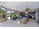 Comfortable covered patio featuring an outdoor kitchen, stone fireplace, and views of the pool and landscaped yard at 5429 County Road 125, Wildwood, FL 34785