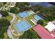 Aerial view shows tennis courts and recreational facilities surrounded by trees at 5512 Rosewall Cir, Leesburg, FL 34748