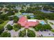 Aerial view of community center featuring a pool, tennis courts, ample parking, and surrounding neighborhood with trees and lakes at 5512 Rosewall Cir, Leesburg, FL 34748