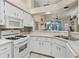 Bright kitchen with white cabinetry and appliances, featuring a backsplash and a view of the living room at 5512 Rosewall Cir, Leesburg, FL 34748
