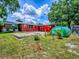Spacious backyard with a greenhouse, red siding, and various trees at 564 Lancaster Ave, Orange City, FL 32763