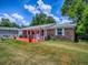 Charming home exterior with a bright orange porch, rocking chairs, and an American flag at 564 Lancaster Ave, Orange City, FL 32763