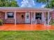 Lovely home featuring a brick exterior, rocking chairs on an orange porch, and well-manicured landscaping at 564 Lancaster Ave, Orange City, FL 32763