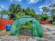 Backyard garden featuring a large greenhouse and red perimeter fencing at 564 Lancaster Ave, Orange City, FL 32763