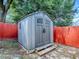 Outdoor storage shed with double doors and steps, adjacent to a red fence at 564 Lancaster Ave, Orange City, FL 32763