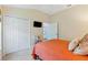 Bright bedroom featuring a closet, TV, doorway, and an orange quilt on the bed at 5746 Botner Dr, The Villages, FL 32163
