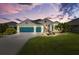 Charming single-story home at dusk with a three-car garage, pretty landscaping, and inviting curb appeal at 5746 Botner Dr, The Villages, FL 32163