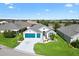 Elevated angle of single-story home features a 3-car garage, pretty landscaping and community pond nearby at 5746 Botner Dr, The Villages, FL 32163