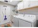 Functional laundry room featuring a washer, dryer, cabinets, and a stylish floor rug at 5746 Botner Dr, The Villages, FL 32163
