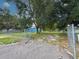Fenced backyard showcasing mature trees, offering shade and privacy with an open gate leading to a blue garage at 5825 Lake Emma Ct, Groveland, FL 34736
