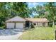 Charming single-story home featuring a stone facade, well-manicured lawn, and attached two-car garage at 5825 Lake Emma Ct, Groveland, FL 34736