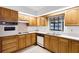 Functional kitchen with wood cabinets, white appliances, and a large window overlooking the backyard at 5825 Lake Emma Ct, Groveland, FL 34736