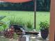 Backyard pond and small waterfall feature with lawn and natural Florida landscape at 672 E Belt Ave, Bushnell, FL 33513
