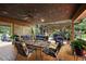 This covered back porch features a ceiling fan, comfortable seating, and direct access to the outdoor kitchen at 672 E Belt Ave, Bushnell, FL 33513