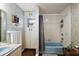 Bright bathroom featuring a blue bathtub with shower, storage cabinets, and floral-patterned wallpaper at 672 E Belt Ave, Bushnell, FL 33513