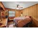 Cozy bedroom with wood paneled walls, a ceiling fan, natural lighting, and an inviting bed at 672 E Belt Ave, Bushnell, FL 33513