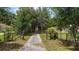 Long driveway through mature trees leads up to the house with fenced in green pastures on both sides of the drive at 672 E Belt Ave, Bushnell, FL 33513