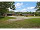 Expansive exterior with mature trees, long driveway, wooden home with stone accents, and a side-entry two-car garage at 672 E Belt Ave, Bushnell, FL 33513