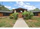 Custom home with wooden doors, stone accents, cedar siding, mature palms, and well-maintained landscaping at 672 E Belt Ave, Bushnell, FL 33513