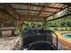 This back yard features a hot tub spa under a pergola next to the pool surrounded by tropical vegetation at 672 E Belt Ave, Bushnell, FL 33513