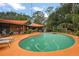 This backyard features an in-ground pool with orange concrete patio with an orange sunshade canopy over the pool area at 672 E Belt Ave, Bushnell, FL 33513