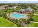 An aerial view of a resort-style swimming pool surrounded by lush landscaping, houses, and palm trees at 752 Sandy Bar Dr, Winter Garden, FL 34787