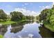 Scenic view of a tranquil pond reflecting the sky, framed by mature trees and green lawns at 752 Sandy Bar Dr, Winter Garden, FL 34787