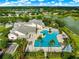 Aerial view of the community pool and clubhouse, including a hot tub, lounge chairs, and mature landscaping at 8045 Waterbury Way, Mount Dora, FL 32757