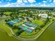 An elevated view of tennis courts within a community recreational area, complemented by trees and a lake at 8045 Waterbury Way, Mount Dora, FL 32757