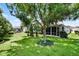 Spacious backyard with well-maintained lawn, mature trees, and the screened lanai of the home at 8960 Se 178Th Muirfield Pl, The Villages, FL 32162